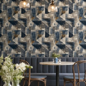 Puede incluir: Interior de restaurante con papel pintado geométrico en tonos azules, grises y marrones. Se observa una mesa redonda, sillas y un banco azul. Dos lámparas colgantes iluminan el espacio, creando una estética moderna.