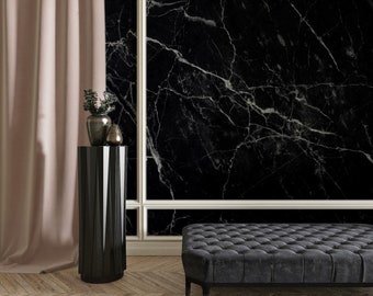May include: A black and white marble patterned wallpaper with a white trim. A black pedestal table with a plant and a decorative object on top. A black tufted bench in front of the wall.