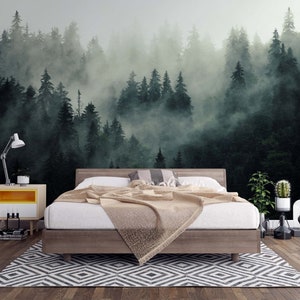 May include: A bedroom with a forest mural. The bed has a wooden frame and a beige blanket. A yellow and white nightstand with a lamp and a black and white patterned rug are in the foreground. The mural depicts a misty forest.