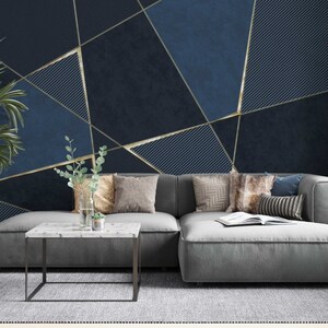May include: A gray sectional sofa with pillows sits in front of a wall with a geometric pattern of gold lines on a dark blue background.