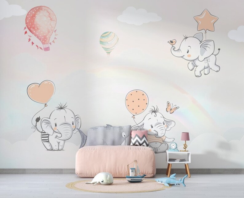 May include: A nursery room with a pink couch and a white wall with a rainbow, clouds, and cute elephant illustrations. The elephants are holding balloons in the shape of hearts and stars.
