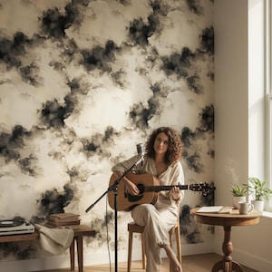 May include: Acoustic guitar with a microphone stand in front of a woman sitting on a wooden stool. The room has a cloud-patterned wallpaper and a wooden floor. A small table with a coffee cup and plants is to the right.