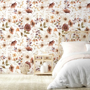 Puede incluir: Una cama blanca con un edred&oacute;n blanco y una manta rosa. La cabecera est&aacute; hecha de rat&aacute;n tejido y la pared detr&aacute;s de la cama est&aacute; cubierta con un papel tapiz floral con fondo blanco y flores marrones, naranjas y moradas.