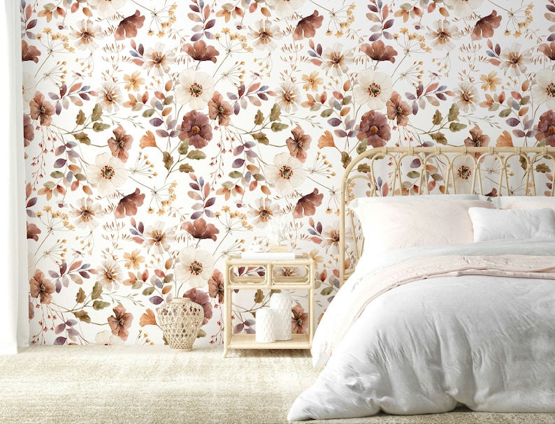 Puede incluir: Una cama blanca con un edred&oacute;n blanco y una manta rosa. La cabecera est&aacute; hecha de rat&aacute;n tejido y la pared detr&aacute;s de la cama est&aacute; cubierta con un papel tapiz floral con fondo blanco y flores marrones, naranjas y moradas.