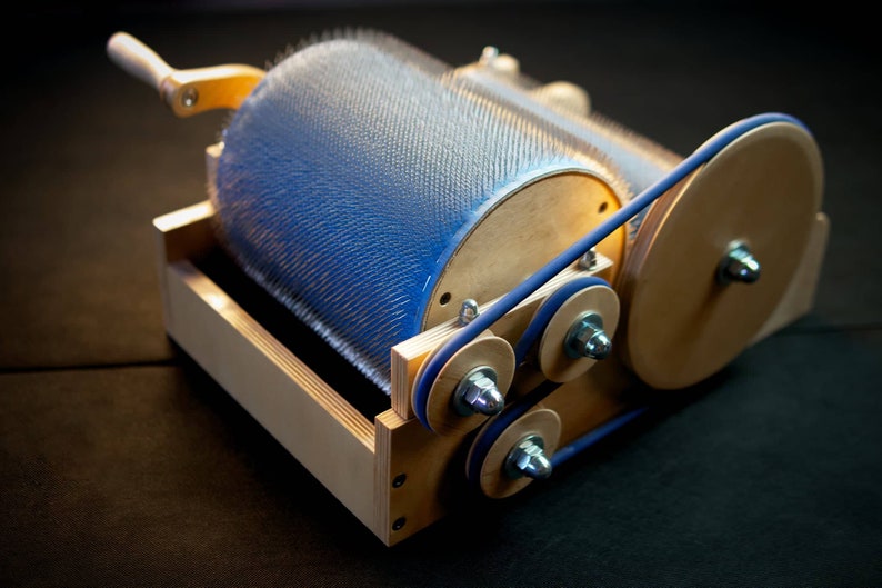 Puede incluir: Una m&aacute;quina de madera con un rodillo de cerdas azules y una correa azul. La m&aacute;quina tiene un mango de madera y una base de madera.