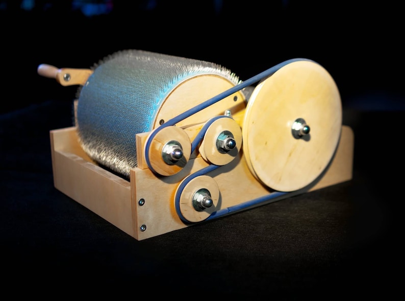 Puede incluir: Una m&aacute;quina de madera con una correa azul y un cepillo giratorio. El cepillo est&aacute; hecho de metal y tiene muchas cerdas peque&ntilde;as. La m&aacute;quina est&aacute; sobre una superficie negra.