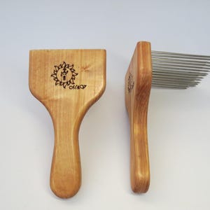 Puede incluir: Dos peines de madera con un peine de metal en un lado. El mango de madera tiene un diseño de sol con el texto "CRAF" quemado en la madera.