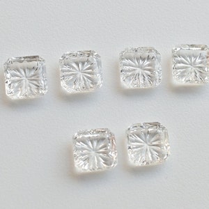 May include: Six clear glass square-shaped buttons with a starburst design.
