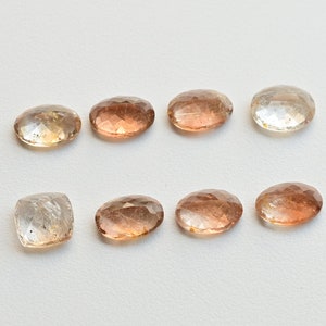 May include: Eight faceted gemstones in various shades of brown and clear. The gemstones are oval and rectangular in shape.