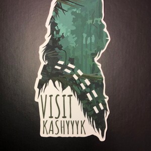 May include: A green and white sticker with a silhouette of Chewbacca, a character from Star Wars, with the text "Visit Kashyyyk" underneath.