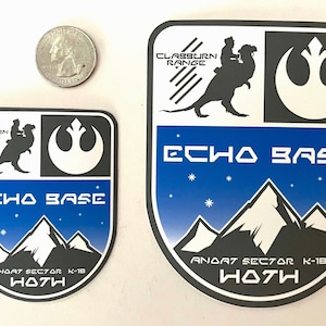 May include: Two black and white stickers with a blue background. The stickers feature a Rebel Alliance symbol, a creature from the Star Wars universe, and the text "Echo Base" and "Andat Sector K-18 Hoth".