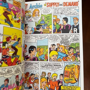 May include: A comic book page featuring Archie and his friends discussing supply and demand. The comic book panel shows a group of teenagers talking about Hostess Twinkies. The text in the comic book panel reads "Supply and Demand" and "Hostess Twinkies Cakes are always in demand with people with good taste." The image also includes a Hostess Twinkies box with the text "You get a big delight in every bite of Hostess Twinkies Cakes."