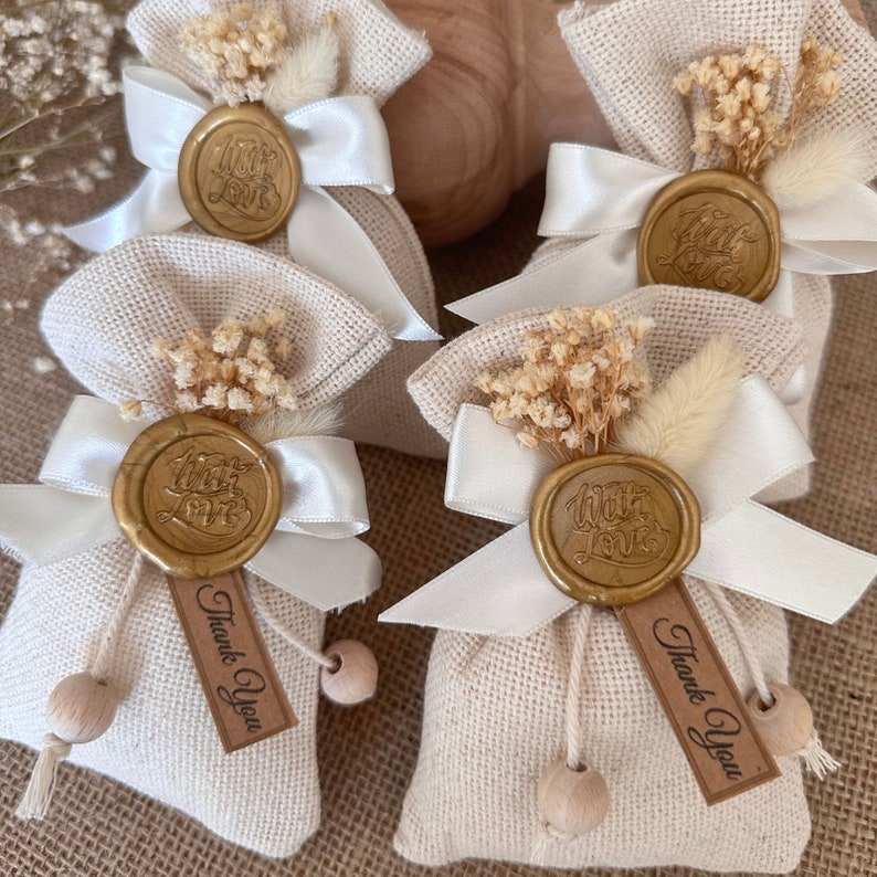 May include: Set of five small burlap bags with white ribbon and a gold wax seal that says "With Love". Each bag has dried flowers and a tag that says "Thank You".