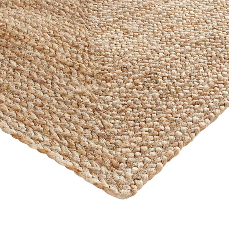May include: A close-up of a natural fiber rug with a woven texture. The rug is a light brown color and has a slightly rough surface.