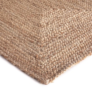 May include: A close-up of a natural fibre rug made from jute. The rug has a woven texture and a light brown colour.