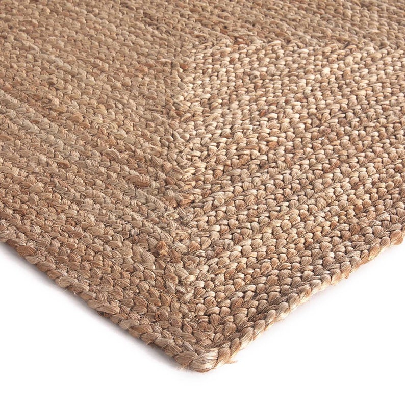 May include: A close-up of a natural fibre rug made from jute. The rug has a woven texture and a light brown colour.