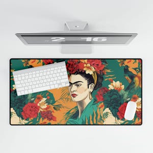 May include: A colourful mouse mat featuring a portrait of Frida Kahlo with flowers in her hair. The background is a vibrant green with orange and red flowers. Two birds are perched on a branch in the top right corner.