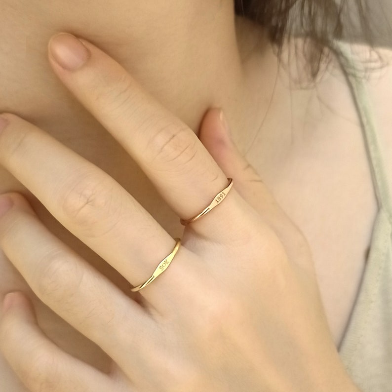 May include: Two gold rings with engraved text. The top ring has the year "1991" engraved on it. The bottom ring has the initials "S.W." engraved on it.