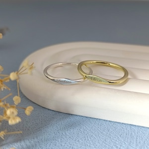 May include: Two thin gold and silver rings with the names "Eileen" and "Jackson" engraved on them.