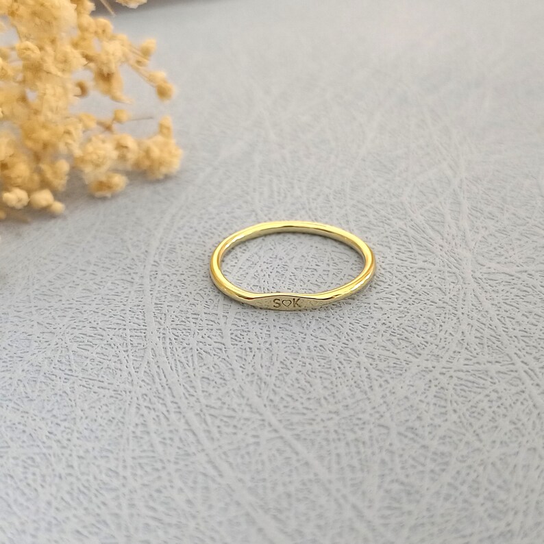 May include: A thin gold band ring with the inscription "SOK" on the front.