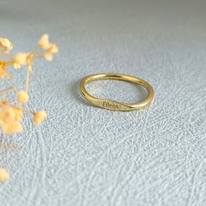 May include: A thin gold band ring with the name "Eileen" engraved on the side.