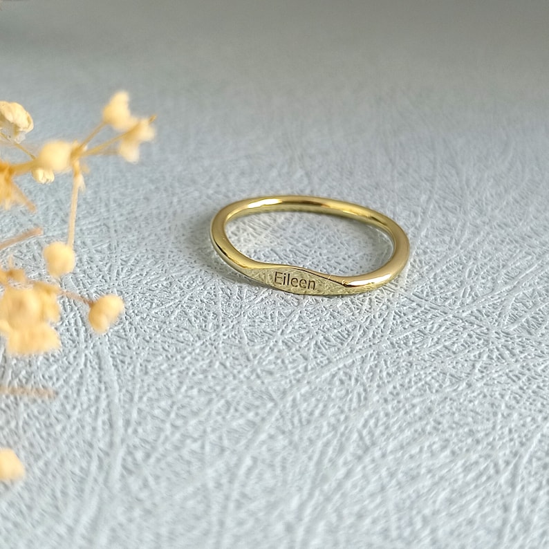 May include: A thin gold band ring with the name "Eileen" engraved on the side.