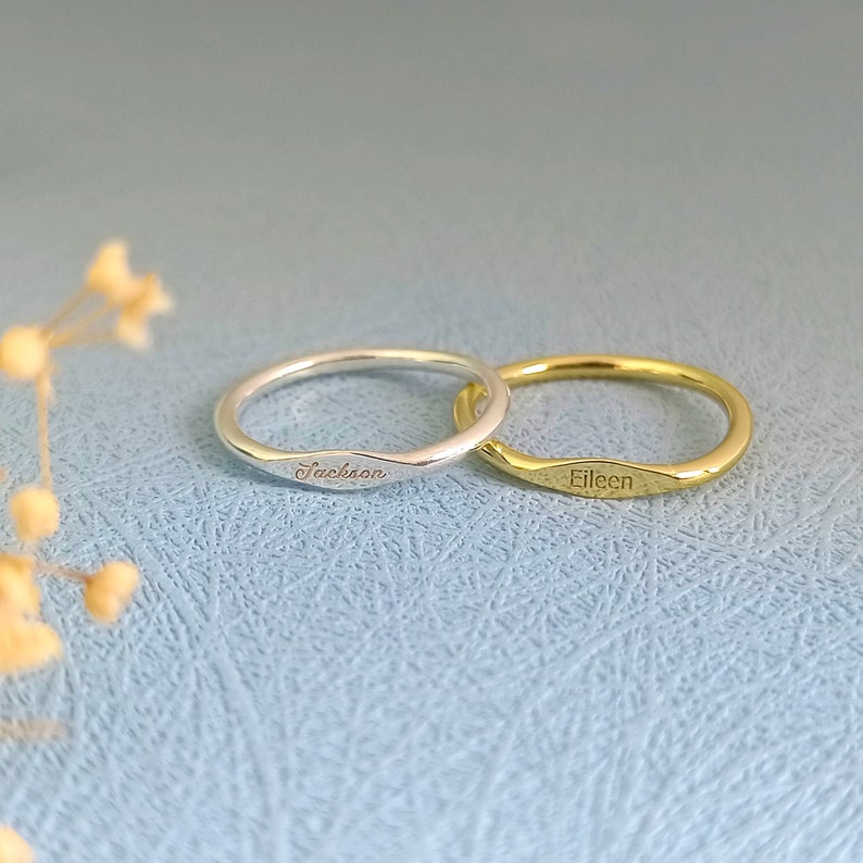 May include: Two thin, engraved rings, one silver and one gold. The silver ring says "Jackson" and the gold ring says "Eileen".