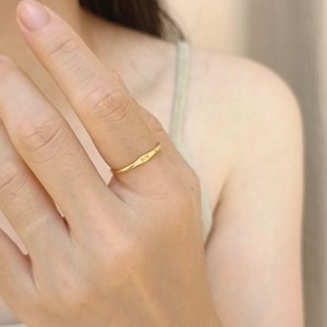 May include: A gold band ring with the word "SOX" engraved on the top. The ring is worn on a person's finger.