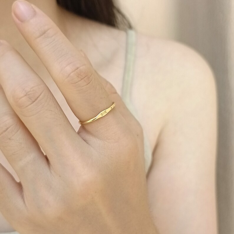 May include: A gold band ring with the word "SOX" engraved on the top. The ring is worn on a person's finger.