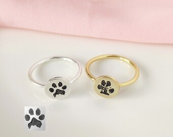 May include: Two rings with a paw print design. One ring is silver and the other is gold.