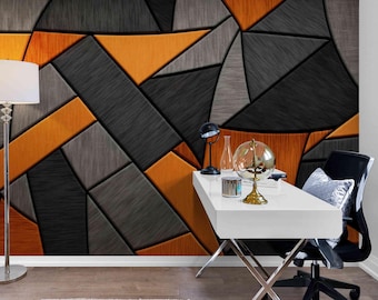 May include: Geometric wall art featuring a modern design with orange, gray, and black panels. The abstract pattern creates a textured effect, suitable for interior decor. The image also shows a white desk, a lamp, and a chair.