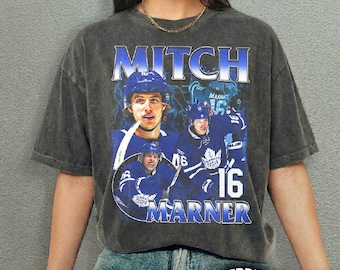 May include: Dark gray t-shirt featuring a graphic of hockey player Mitch Marner in a blue uniform. The design includes the name "Mitch Marner" and the number "16" in a stylized font. The shirt has a vintage, distressed look.