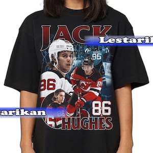 May include: Black t-shirt featuring a vintage-style graphic of a hockey player. The design includes the name "JACK" in red, the number "86", and the name "HUGHES". The player is shown in action with a hockey stick.