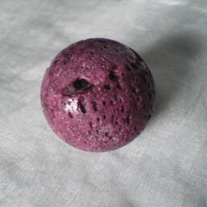 May include: A round, purple, textured ball with a small hole in the centre.