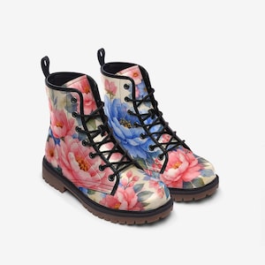 May include: A pair of floral print combat boots. The boots feature a cream-colored background with pink and blue peony flowers. They have black laces, a black pull tab, and a brown sole.