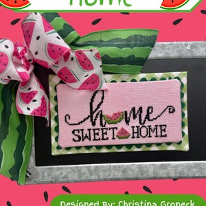 May include: A decorative piece with a watermelon theme. The image features a pink cross-stitched sign that reads "Home Sweet Home" with a watermelon slice accent. A matching bow and ribbon are also included, all set against a watermelon-themed background.