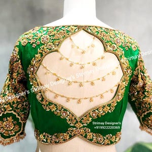 May include: Green and gold embroidered blouse with a low back and a decorative chain detail. The blouse is designed in a traditional Indian style.