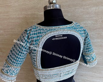 May include: A teal blouse featuring intricate silver embroidery and beadwork across the sleeves and back. The garment has a large, rounded cutout on the back and is finished with small white hanging beads along the sleeve edges. Text reads Strimay +919922220369.
