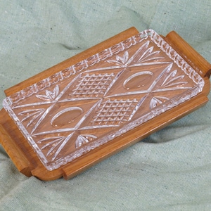 Könnte beinhalten: Ein Holztablett mit einem klaren Glaseinsatz mit Diamantenmuster. Das Tablett hat eine natürliche Holzoptik und ist perfekt zum Servieren von Snacks oder Vorspeisen.