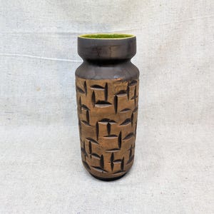 Könnte beinhalten: Eine Vintage-Keramikvase mit einem strukturierten, geometrischen Muster in Braun- und Schwarztönen. Die Vase hat einen breiten Boden, einen schmalen Hals und einen grünen Innenraum. Das Design erinnert an die moderne Einrichtung der Mitte des Jahrhunderts.