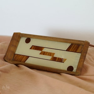 Könnte beinhalten: Ein Holztablett mit einem geometrischen Design in Braun und Weiß. Das Tablett hat einen Glaseinsatz mit einem geometrischen Muster in Braun und Weiß.