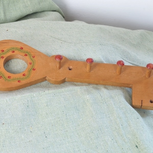 Könnte beinhalten: Wandhaken aus Holz in Schlüsselform mit fünf roten Knöpfen und einem grün-roten Design.