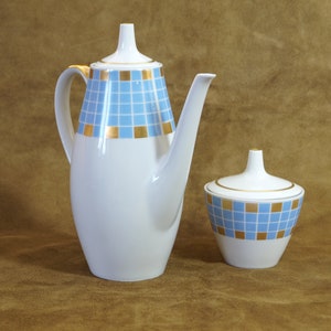 Könnte beinhalten: Ein weißes Keramik-Kaffee- und Zuckerset mit einem geometrischen Muster in Blau und Gold. Die Kanne hat einen Deckel und einen Ausguss. Die Schale hat einen Deckel.