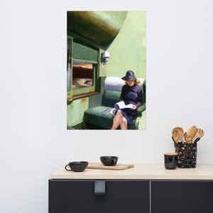 May include: A woman in a black hat and dress sits in a green train compartment, reading a book. The train car has a window with a view of a landscape.