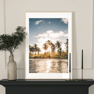 May include: A framed photograph of a tropical beach scene with palm trees and a bright blue sky. The photo is hanging above a black fireplace mantel with a table setting in front of it.