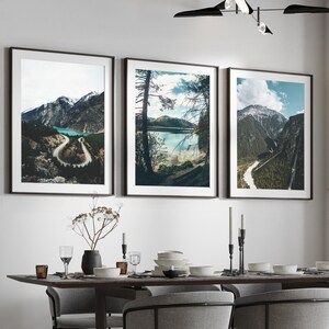 May include: A dining room with a wooden table and six chairs. The table is set with plates, glasses, and silverware. There are three framed landscape photographs on the wall behind the table. A black modern chandelier hangs above the table.