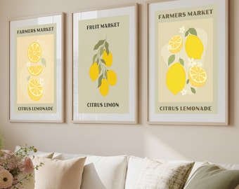 May include: Three framed art prints with a lemon theme. The prints feature yellow lemons and the text "Farmers Market" and "Citrus Lemonade" or "Citrus Limon". The prints are displayed above a white sofa with decorative pillows.