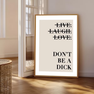 Può includere: Una stampa murale rettangolare in una cornice di legno chiaro con sfondo beige e testo nero. Le parole LIVE, LAUGH e LOVE sono barrate da una linea nera orizzontale, seguite dal testo DON'T BE A DICK scritto in caratteri neri.