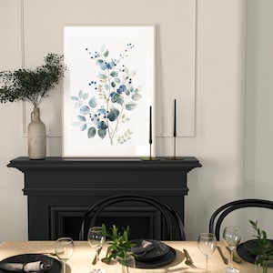 May include: A framed watercolour print of a blue and green floral arrangement with a black fireplace and dining table setting in the background.