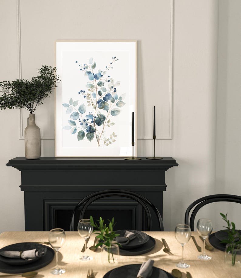 May include: A framed watercolour print of a blue and green floral arrangement with a black fireplace and dining table setting in the background.